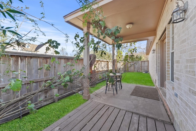 wooden deck with a lawn and a patio