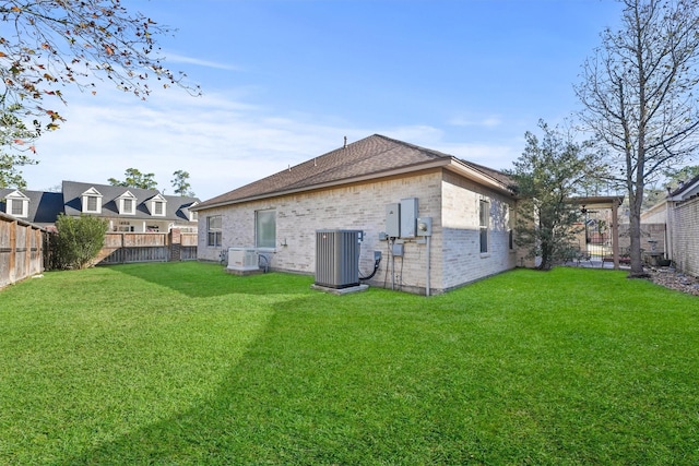 back of property with central AC unit and a lawn