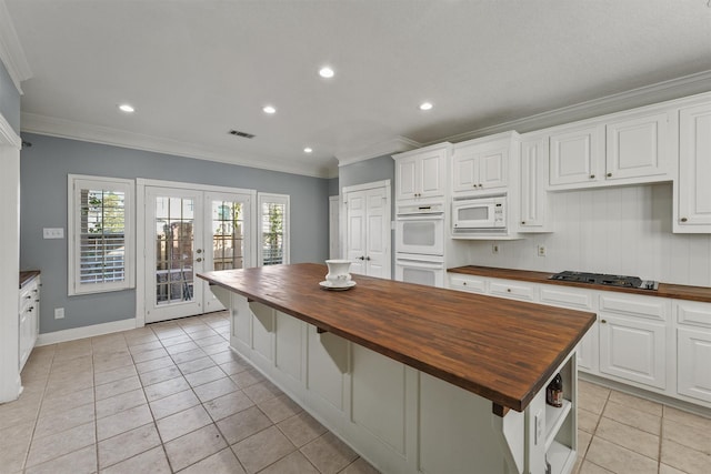 kitchen featuring white cabinetry, butcher block countertops, white appliances, french doors, and a kitchen island