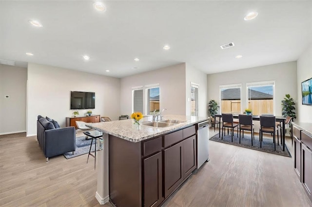 kitchen featuring light hardwood / wood-style flooring, sink, stainless steel dishwasher, a center island with sink, and dark brown cabinets