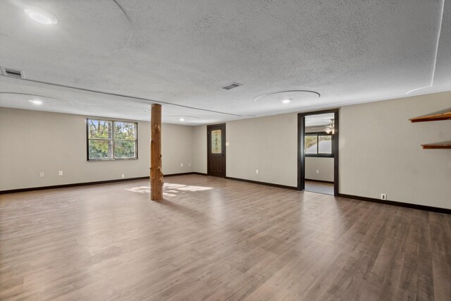 basement featuring wood-type flooring and a textured ceiling