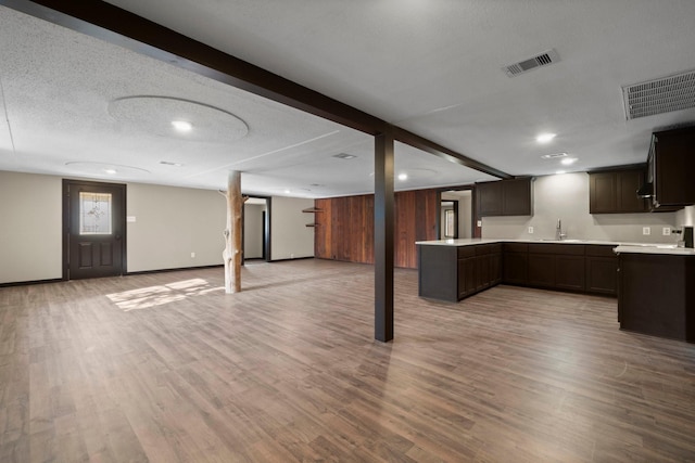 basement with sink, a textured ceiling, and light hardwood / wood-style floors