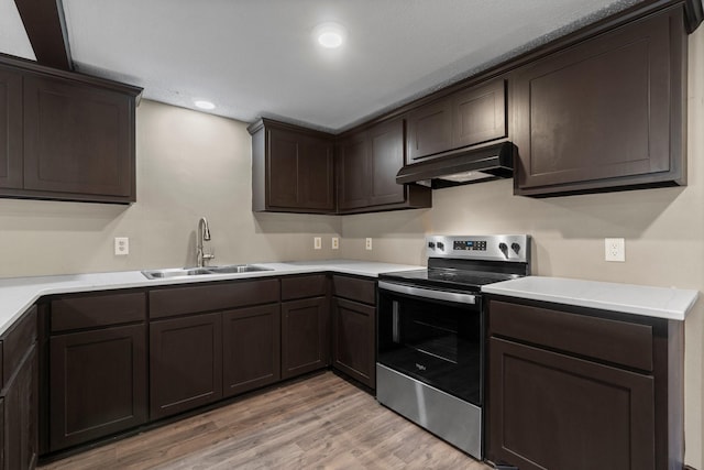 kitchen featuring light wood-type flooring, stainless steel range with electric cooktop, dark brown cabinetry, and sink