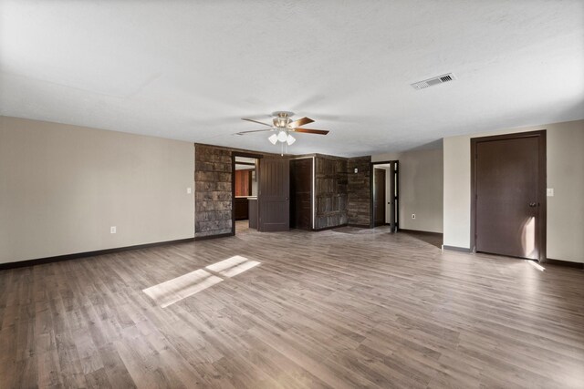 unfurnished living room featuring ceiling fan, hardwood / wood-style floors, and a textured ceiling