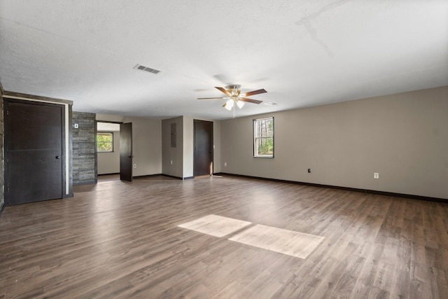 empty room with a textured ceiling, ceiling fan, and dark hardwood / wood-style floors