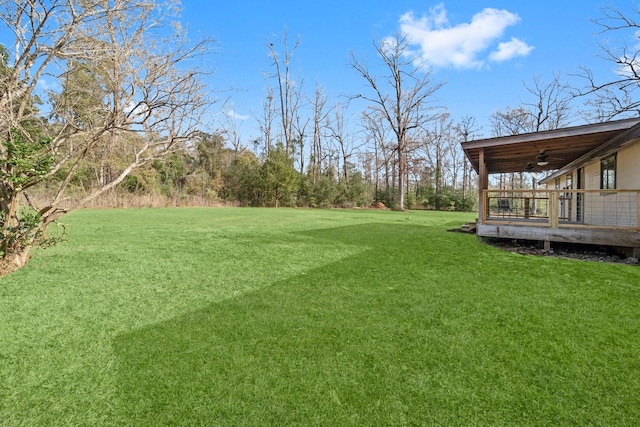 view of yard featuring ceiling fan and a deck