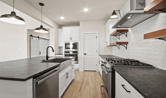 kitchen with a barn door, decorative backsplash, white cabinetry, stainless steel appliances, and island range hood