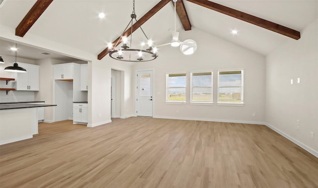 unfurnished living room with high vaulted ceiling, beamed ceiling, a chandelier, and light wood-type flooring