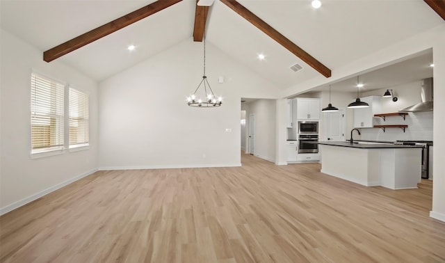 kitchen featuring decorative light fixtures, white cabinetry, wall chimney range hood, and stainless steel range oven