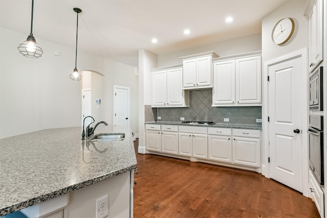 kitchen featuring appliances with stainless steel finishes, tasteful backsplash, pendant lighting, white cabinets, and sink