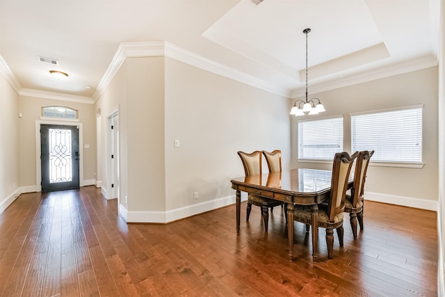 dining space with an inviting chandelier, a wealth of natural light, hardwood / wood-style floors, and a tray ceiling