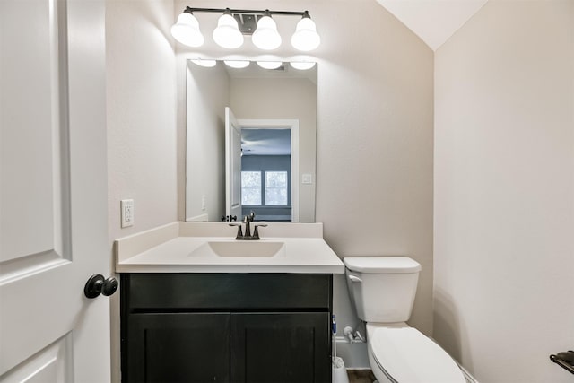 bathroom with toilet, vanity, and vaulted ceiling