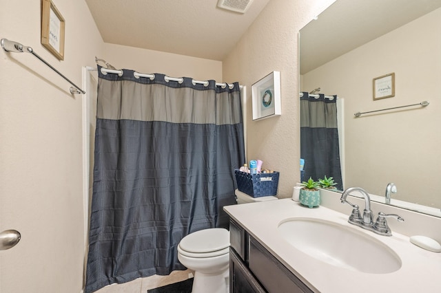 bathroom featuring toilet, vanity, walk in shower, tile patterned floors, and a textured ceiling