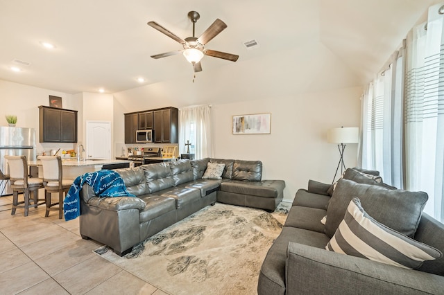 tiled living room featuring ceiling fan, lofted ceiling, and sink