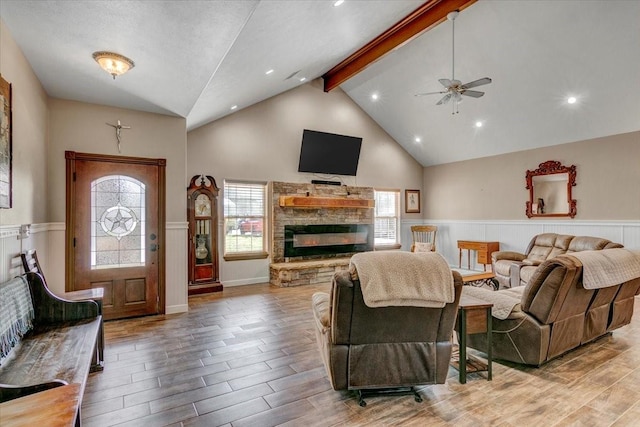 living room featuring ceiling fan, a fireplace, and lofted ceiling with beams