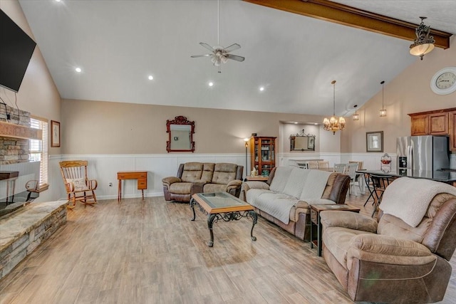 living room with a stone fireplace, beam ceiling, light wood-type flooring, high vaulted ceiling, and ceiling fan with notable chandelier