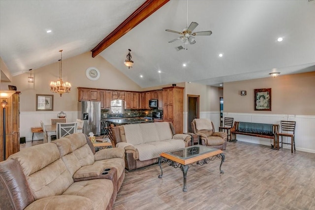 living room with ceiling fan with notable chandelier, light hardwood / wood-style floors, high vaulted ceiling, and beamed ceiling