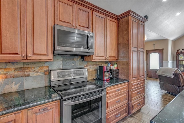 kitchen featuring backsplash, dark stone counters, and stainless steel appliances