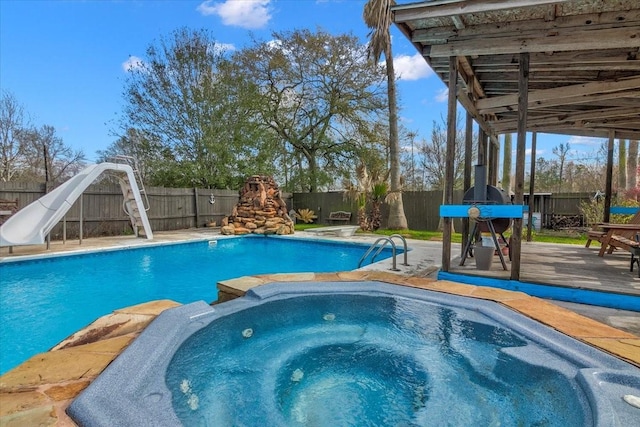 view of pool featuring a water slide and an in ground hot tub