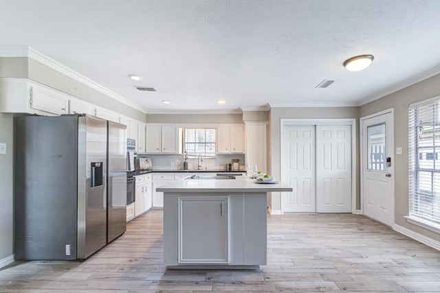 kitchen featuring a kitchen island, stainless steel refrigerator with ice dispenser, white cabinetry, light hardwood / wood-style flooring, and crown molding