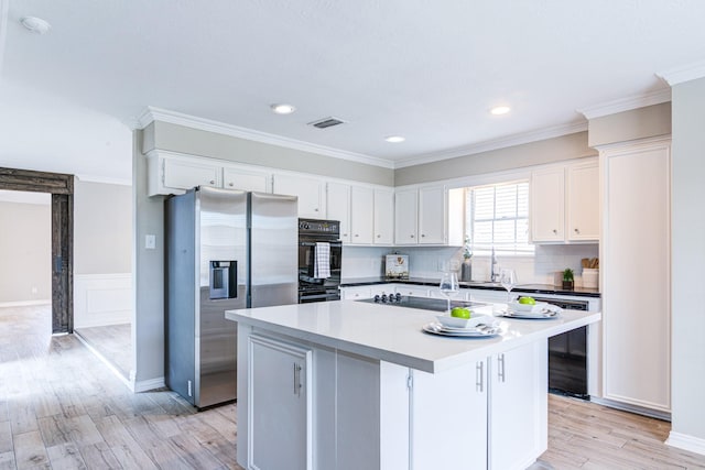 kitchen with light hardwood / wood-style flooring, white cabinets, a center island, and black appliances