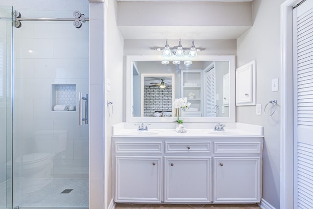 bathroom featuring toilet, ceiling fan, a shower with shower door, and vanity