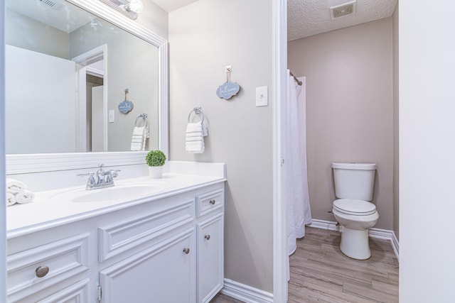 bathroom with hardwood / wood-style flooring, a textured ceiling, toilet, and vanity