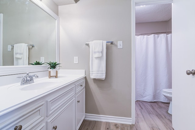 bathroom featuring toilet, vanity, a textured ceiling, and hardwood / wood-style flooring