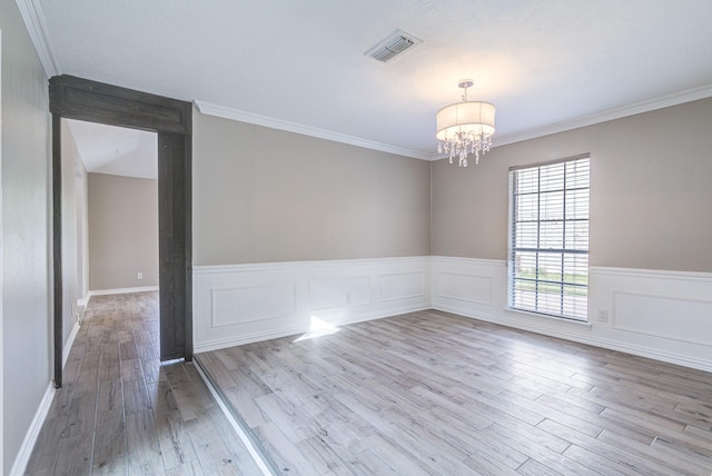 spare room featuring crown molding, a notable chandelier, and light wood-type flooring