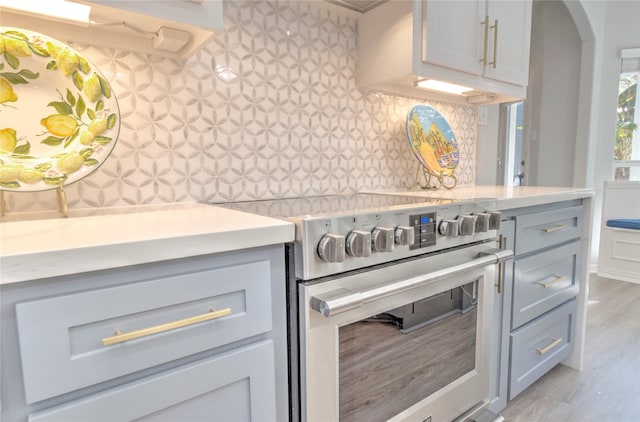 kitchen featuring decorative backsplash, light hardwood / wood-style floors, and stainless steel range with electric cooktop