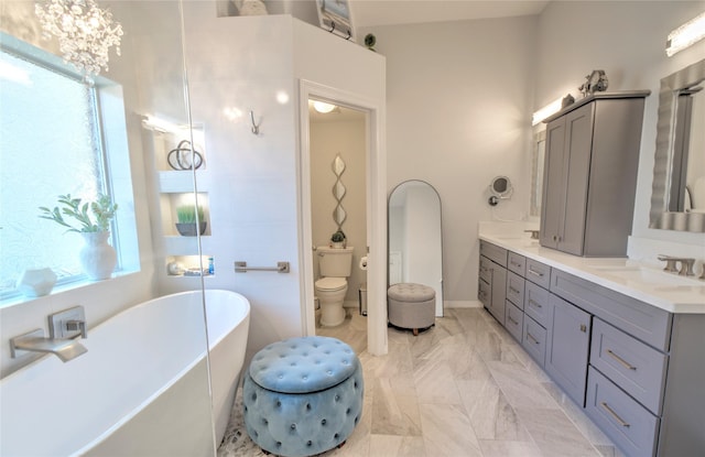 bathroom featuring toilet, a bath, a chandelier, and vanity