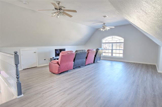 additional living space featuring ceiling fan, a textured ceiling, vaulted ceiling, and light wood-type flooring