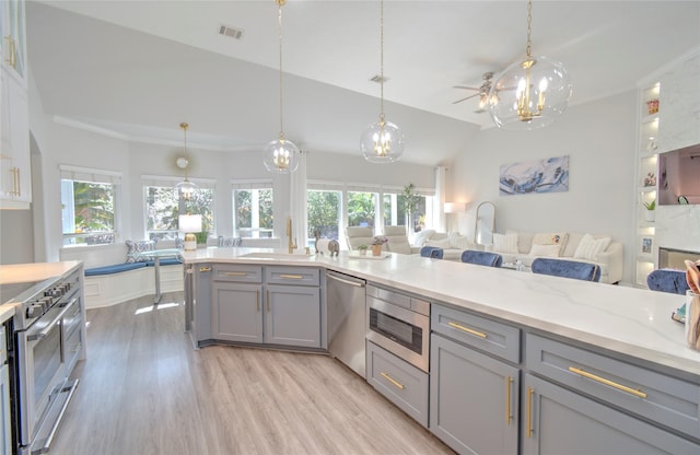 kitchen featuring decorative light fixtures, vaulted ceiling, appliances with stainless steel finishes, and gray cabinetry