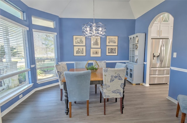 dining space featuring vaulted ceiling, an inviting chandelier, and hardwood / wood-style flooring