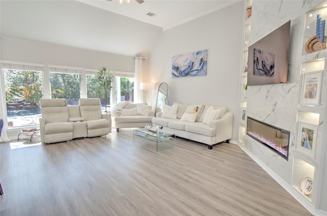 living room featuring lofted ceiling, light wood-type flooring, a fireplace, and ceiling fan