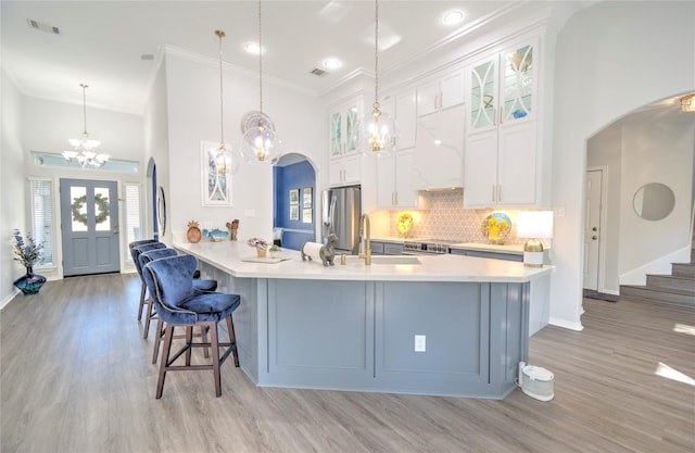 kitchen with backsplash, pendant lighting, white cabinetry, light wood-type flooring, and stainless steel fridge with ice dispenser