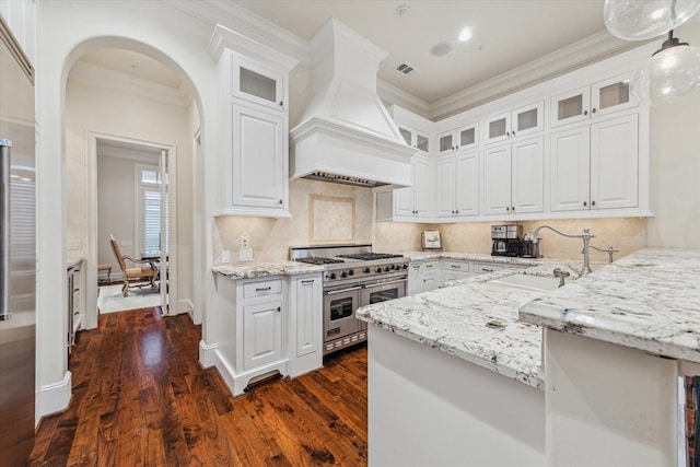 kitchen featuring white cabinetry, premium range hood, range with two ovens, and decorative light fixtures