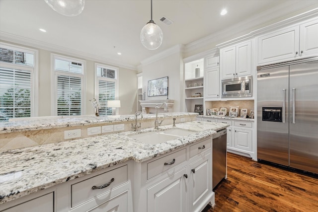 kitchen featuring decorative light fixtures, white cabinets, sink, and built in appliances