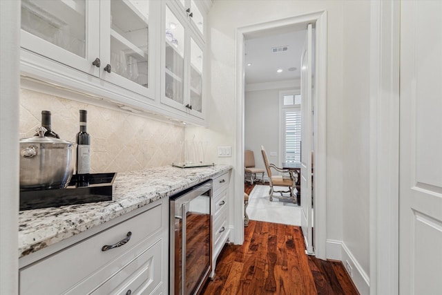 bar with tasteful backsplash, dark wood-type flooring, wine cooler, light stone countertops, and white cabinets