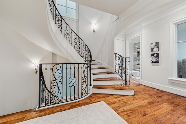 stairs featuring ornamental molding, built in features, and hardwood / wood-style floors