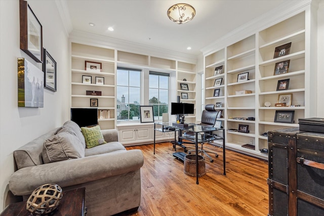 office space featuring built in shelves, wood-type flooring, and crown molding