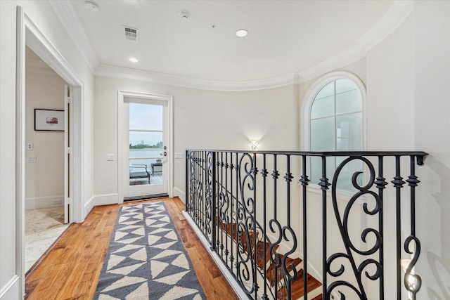 corridor with ornamental molding and light wood-type flooring