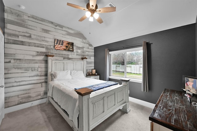 carpeted bedroom with ceiling fan, vaulted ceiling, and wooden walls