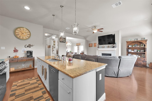 kitchen with pendant lighting, white cabinets, dishwasher, sink, and a center island with sink