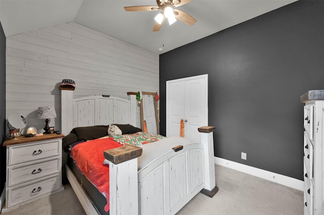 carpeted bedroom featuring vaulted ceiling, ceiling fan, and wood walls