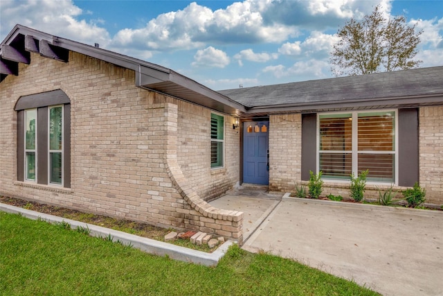 doorway to property featuring a lawn and a patio