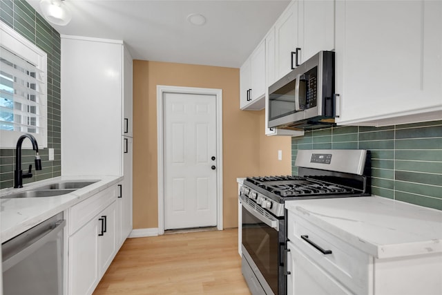 kitchen featuring light hardwood / wood-style floors, sink, white cabinetry, light stone countertops, and stainless steel appliances