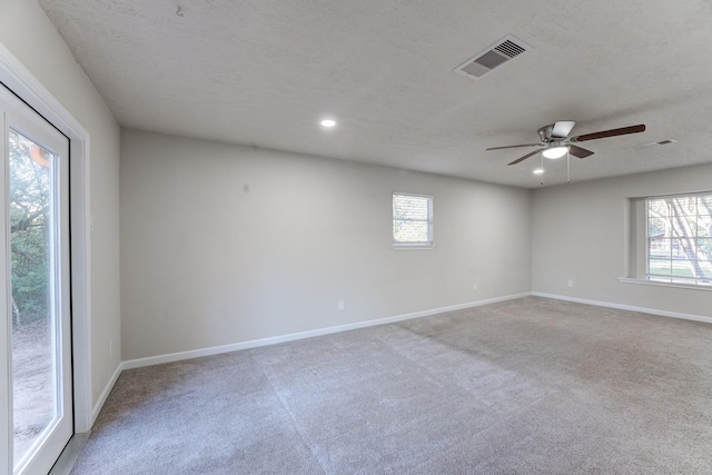 carpeted spare room featuring ceiling fan and a textured ceiling