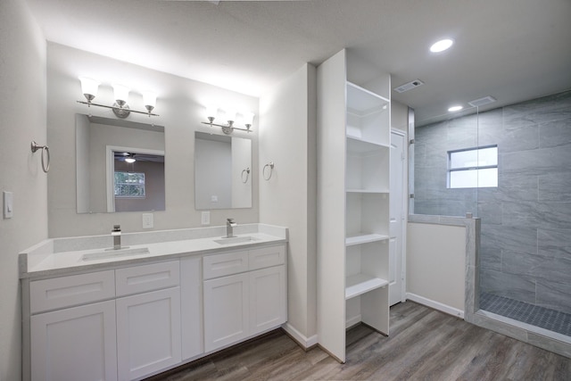 bathroom featuring hardwood / wood-style floors, tiled shower, and vanity