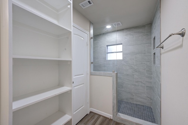 bathroom featuring hardwood / wood-style flooring and tiled shower